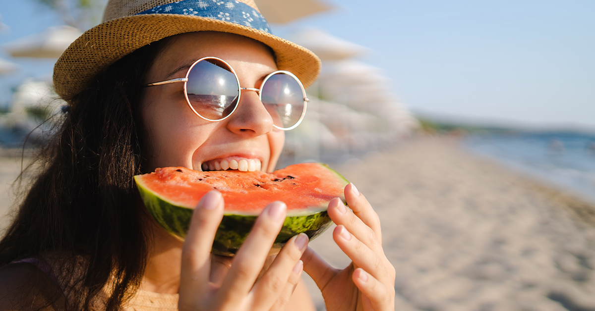 Young woman eating watermelon on the beach
